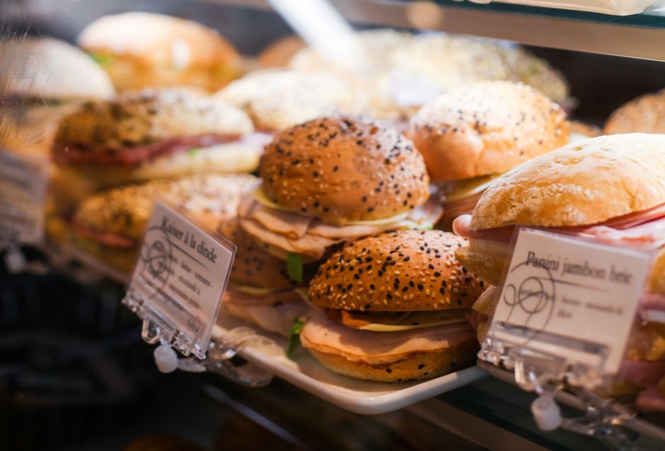 Mini-sandwichs sucrés sur un plateau, garnis de brioche, confiture et fruits, présentés en vitrine.