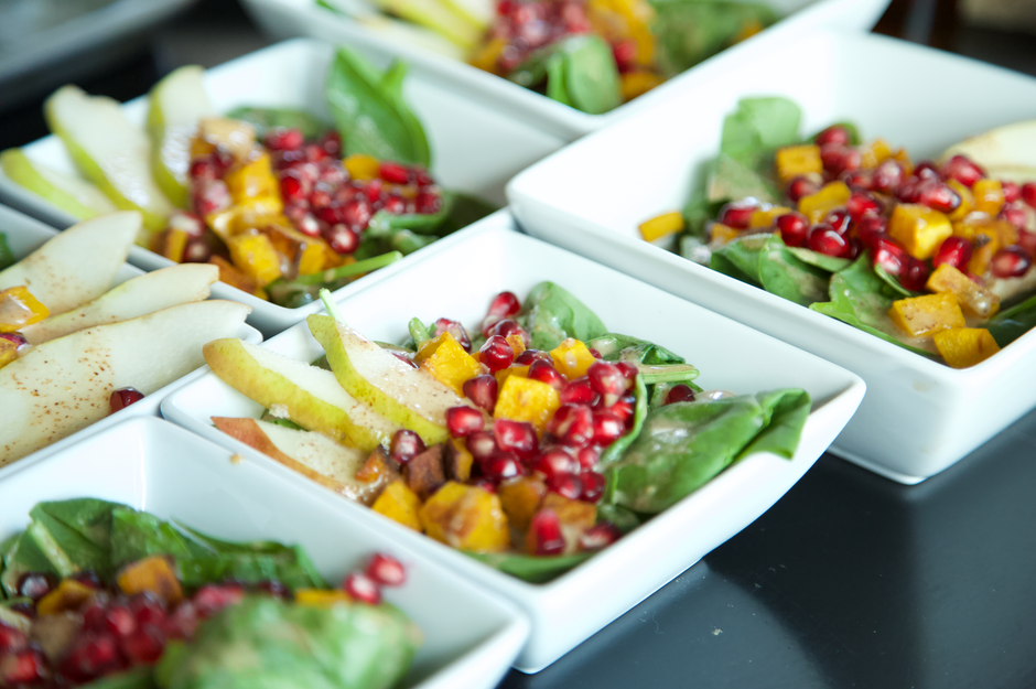 Salade de fruits de saison avec poires, grenade et épinards dans des bols blancs.