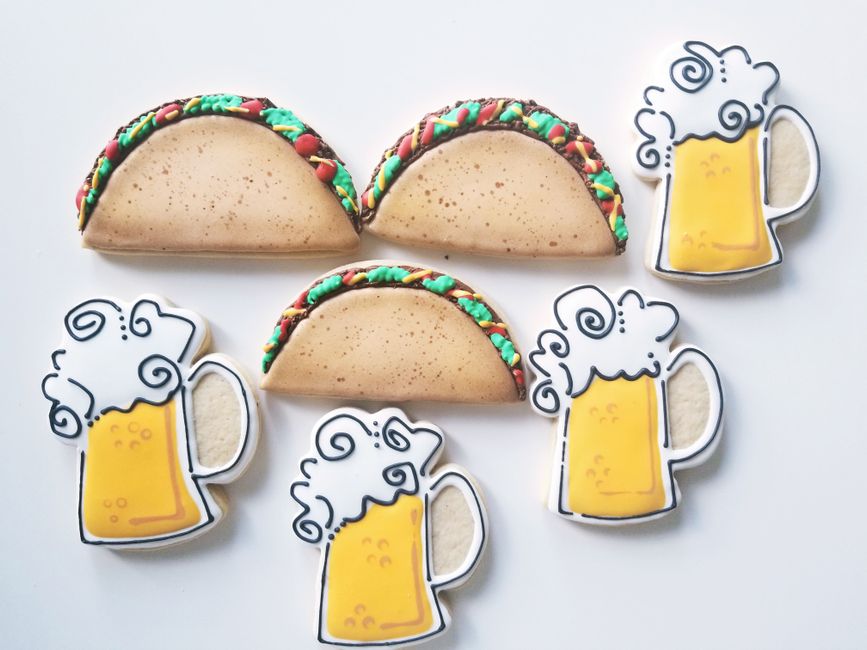 Sablés décorés en forme de tacos et de mugs de bière avec glaçage coloré sur fond blanc.