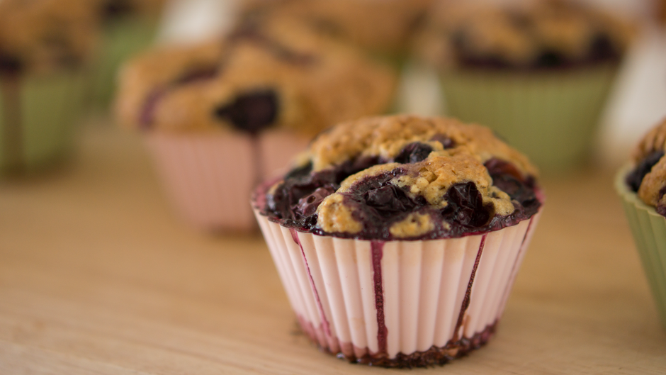 Muffin aux myrtilles dans un moule en silicone, avec d'autres muffins flous en arrière-plan.