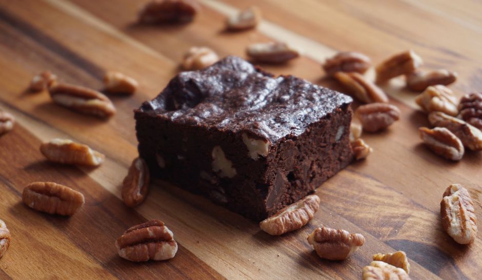 Brownie fondant au chocolat avec des noix de pécan sur une planche en bois.