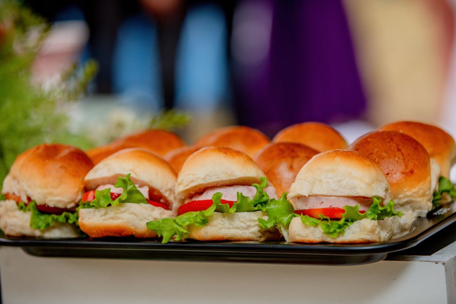 Plateau de mini-sandwichs sucrés en brioche garnis de confiture, fruits et laitue, présentés en rangée.