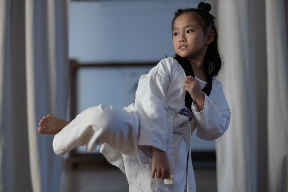 Enfant en kimono de karaté exécutant un coup de pied dans un dojo.