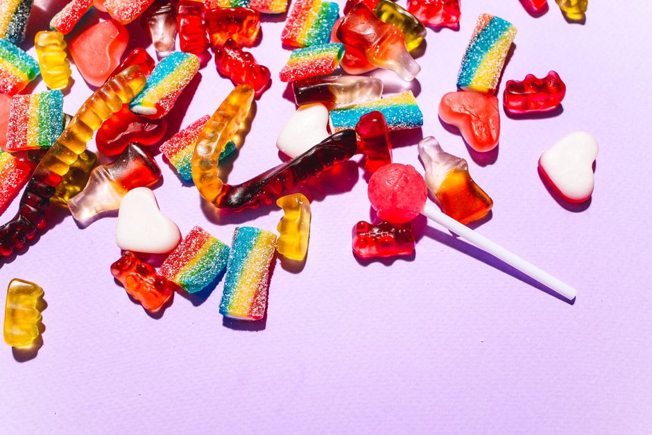 Un mélange coloré de bonbons gélifiés et sucettes sur un fond violet, parfait pour des brochettes sucrées.