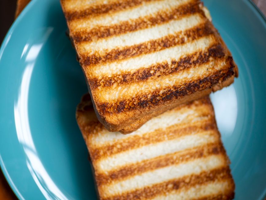 Tartines grillées dorées sur une assiette bleue, prêtes à être garnies pour un goûter sucré-salé.