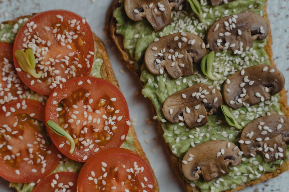 Tartines garnies de tomates et d'avocat avec des champignons, parsemées de graines de sésame.