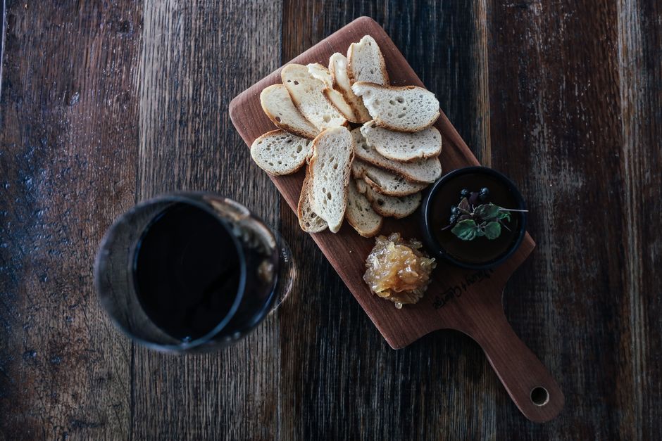 Assiette en bois avec des tranches de pain, confiture et herbes, sur une table en bois.