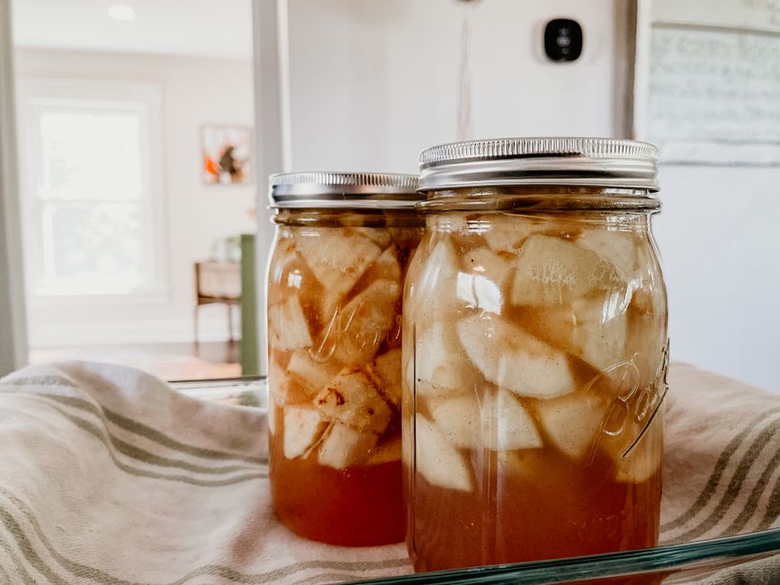 Deux bocaux en verre contenant de la compote de pommes et poires maison, posés sur un linge de cuisine.
