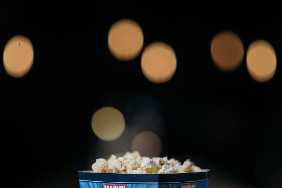Bol de popcorn sucré-salé avec un fond flou de lumières, illustrant des assaisonnements créatifs.