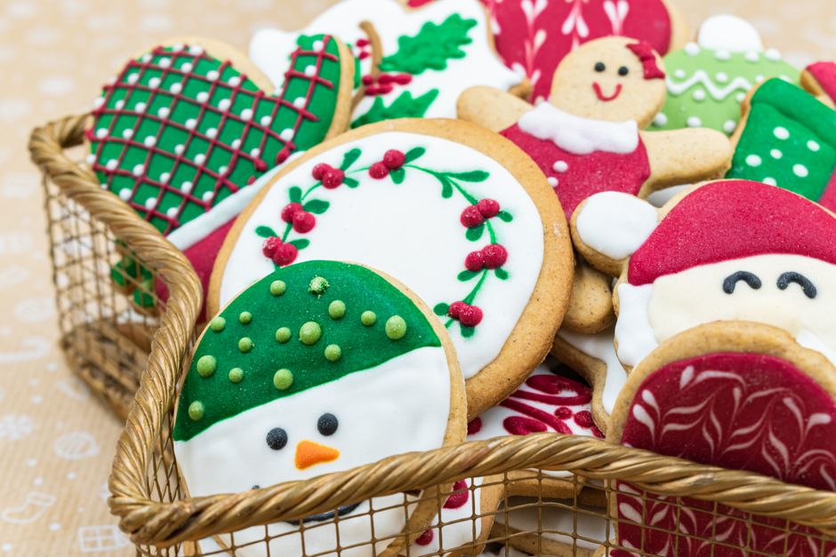 Panier rempli de sablés décorés avec glaçage coloré, représentant des formes de Noël comme des bonhommes de pain d'épice et d