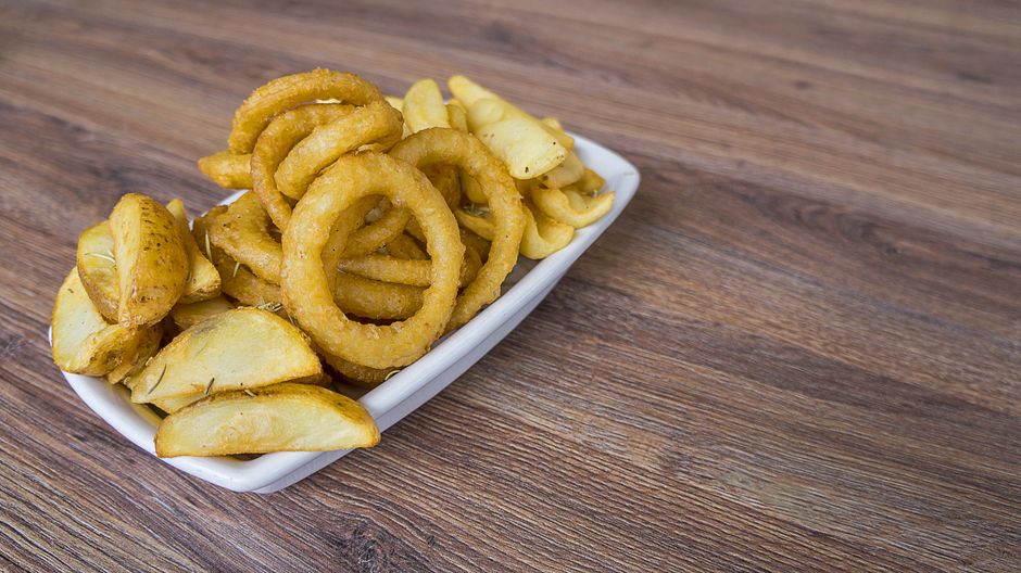 Assiette de frites dorées et d'anneaux d'oignon sur une table en bois, idéale pour un goûter équilibré.
