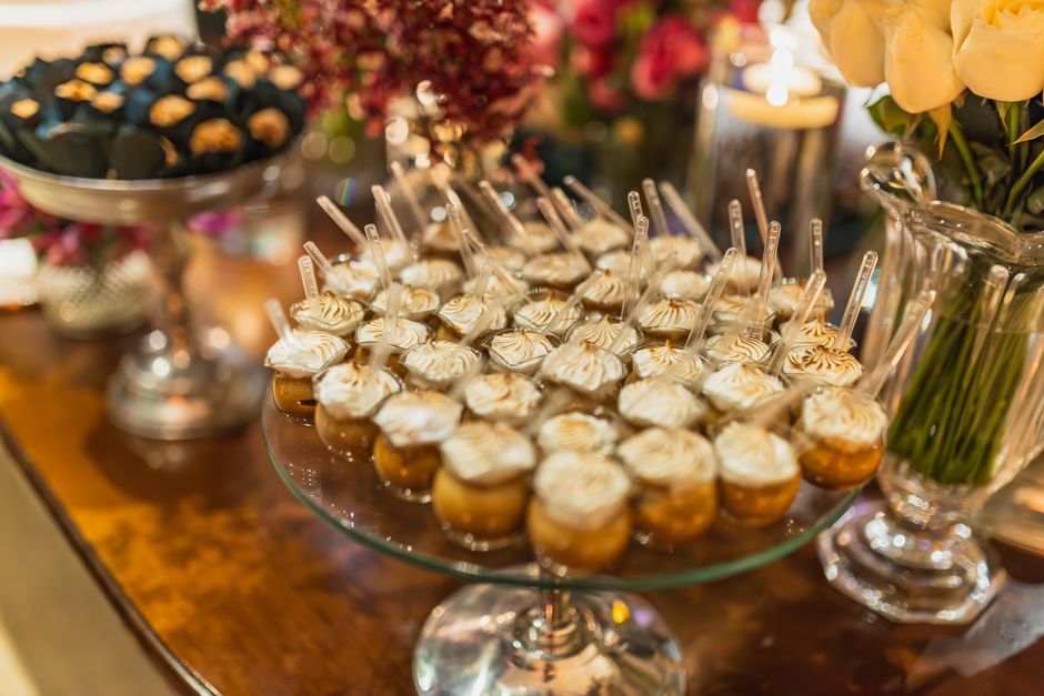 Desserts présentés sur une table, avec des mini-verrines de crème et des douceurs décorées, entourés de fleurs.