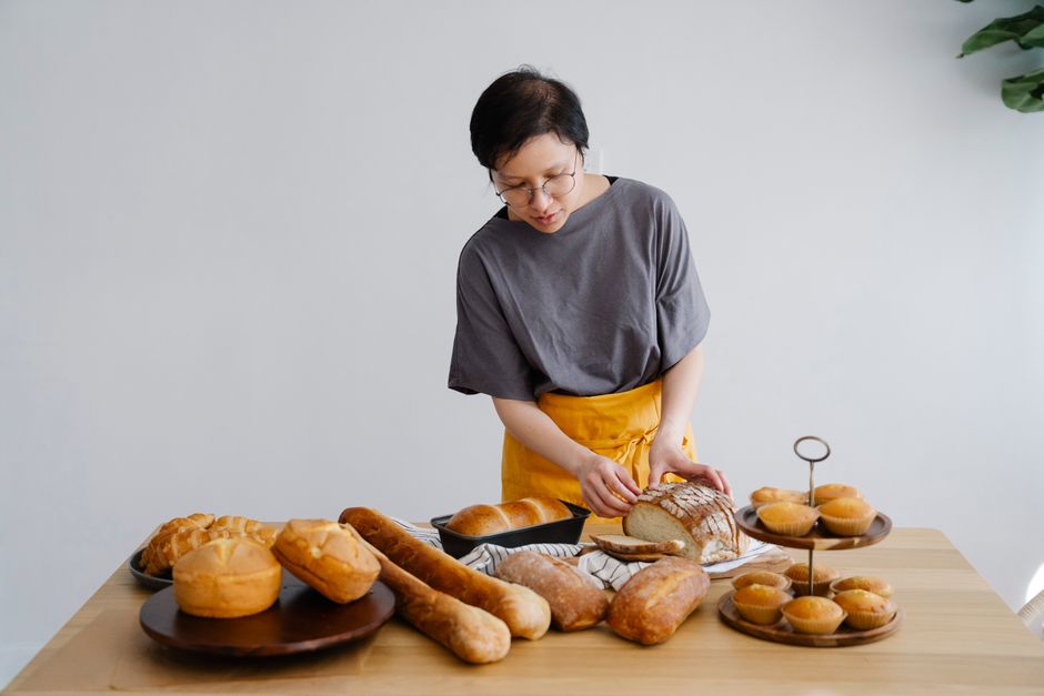 Femme préparant des pains et des pâtisseries sur une table, mettant en avant des alternatives pour un goûter sans allergènes.