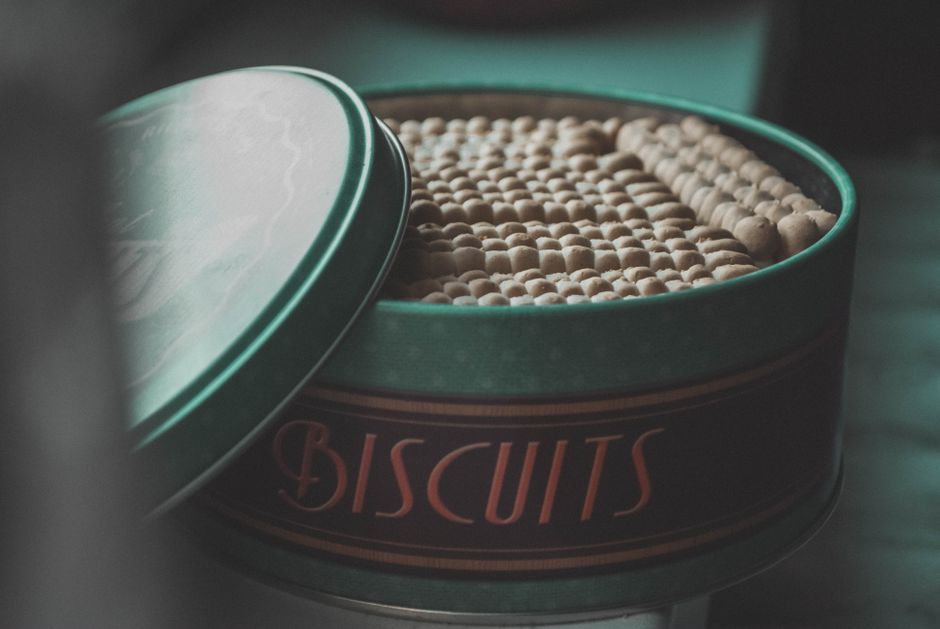 Boîte vintage ouverte contenant des biscuits, sur un fond flou, illustrant la conservation des douceurs.