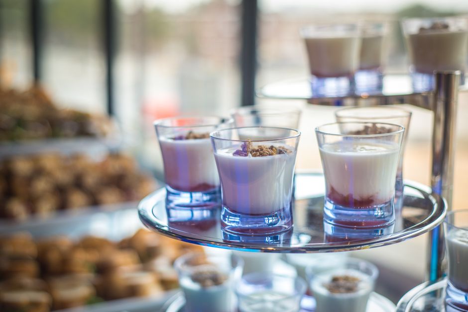 Verrines de fromage blanc avec miel et fruits rouges sur un présentoir en verre, décorées de granola.