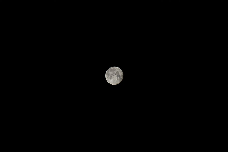 Lune pleine illuminant un ciel noir, créant une atmosphère paisible et nocturne.