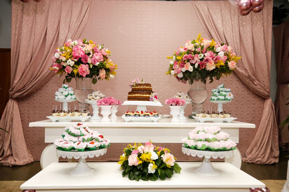 Table décorée pour un anniversaire avec un gâteau central, des fleurs colorées et des douceurs variées.