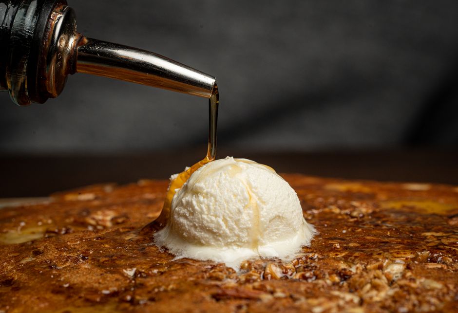 Un pancake épais surmonté d'une boule de glace et arrosé de sirop.