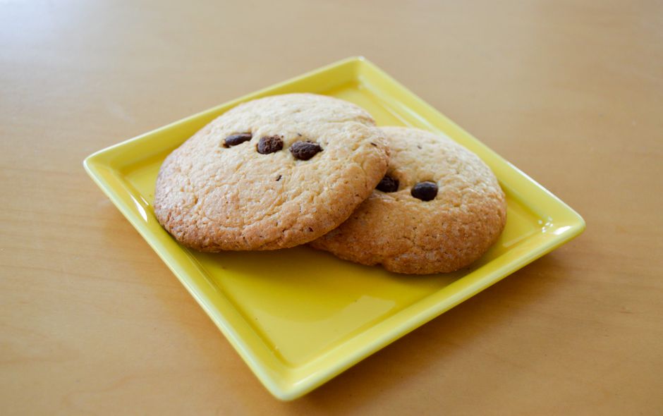 Deux cookies moelleux au chocolat sur une assiette jaune, prêts à être dégustés.